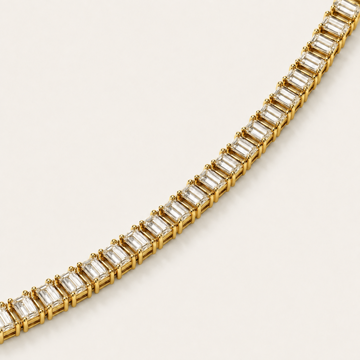 A close-up of a yellow gold tennis bracelet featuring baguette-cut clear stones, set against a clean, off-white background.